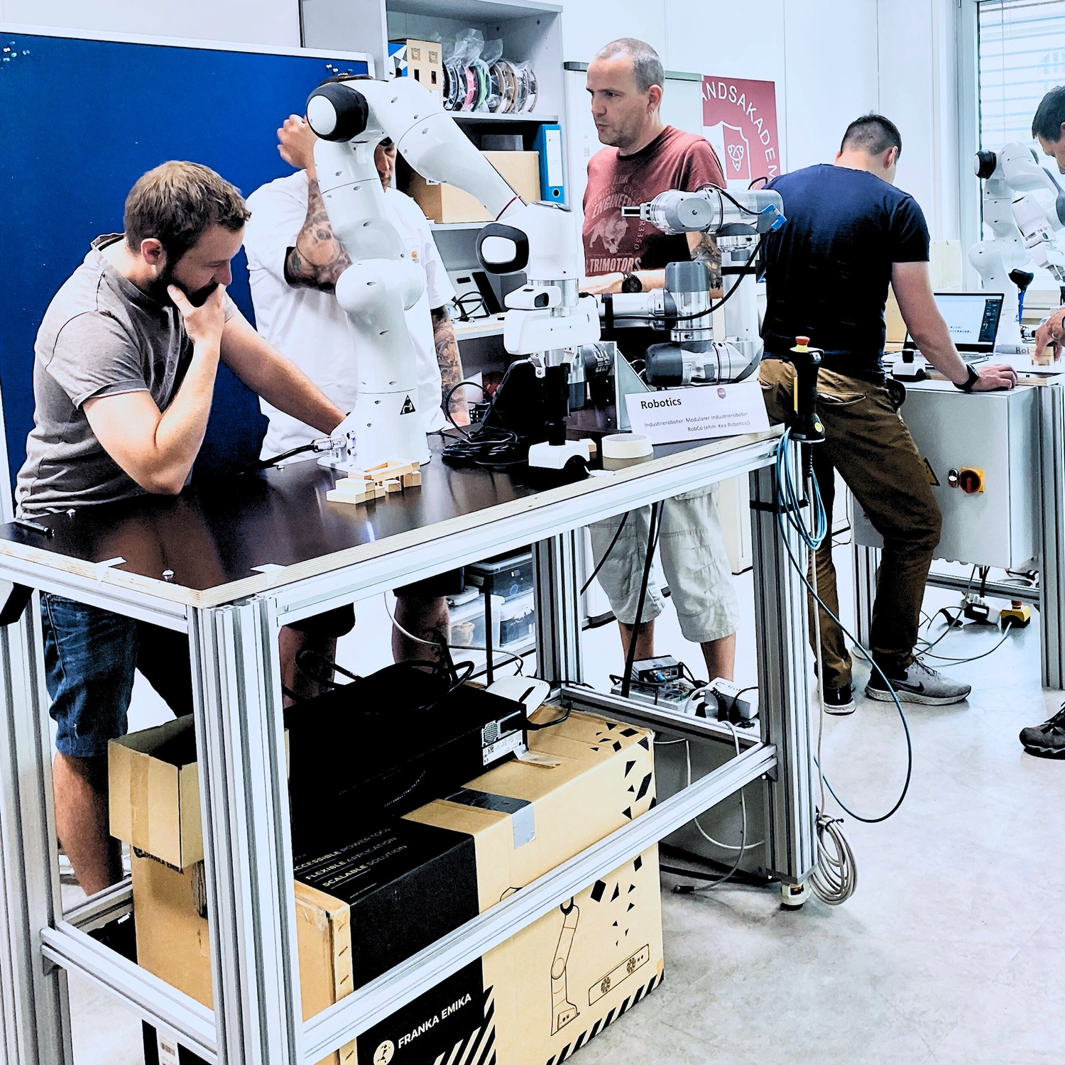 Mehrere Kursteilnehmer programmieren und bedienen kollaborative Roboter in einem Industrie 4.0 Weiterbildungsworkshop.