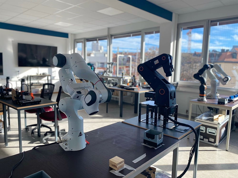 Moderne Robotik-Arbeitsplätze mit Industrierobotern im Technikum der German Academies Munich zur Miete.