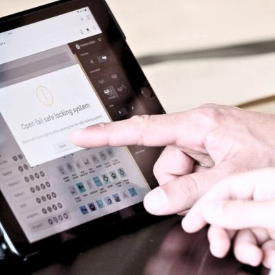Finger tippt auf Warnmeldung „Open fail safe locking system“ auf einem Tablet – praxisnahes Training zur Problemlösung.