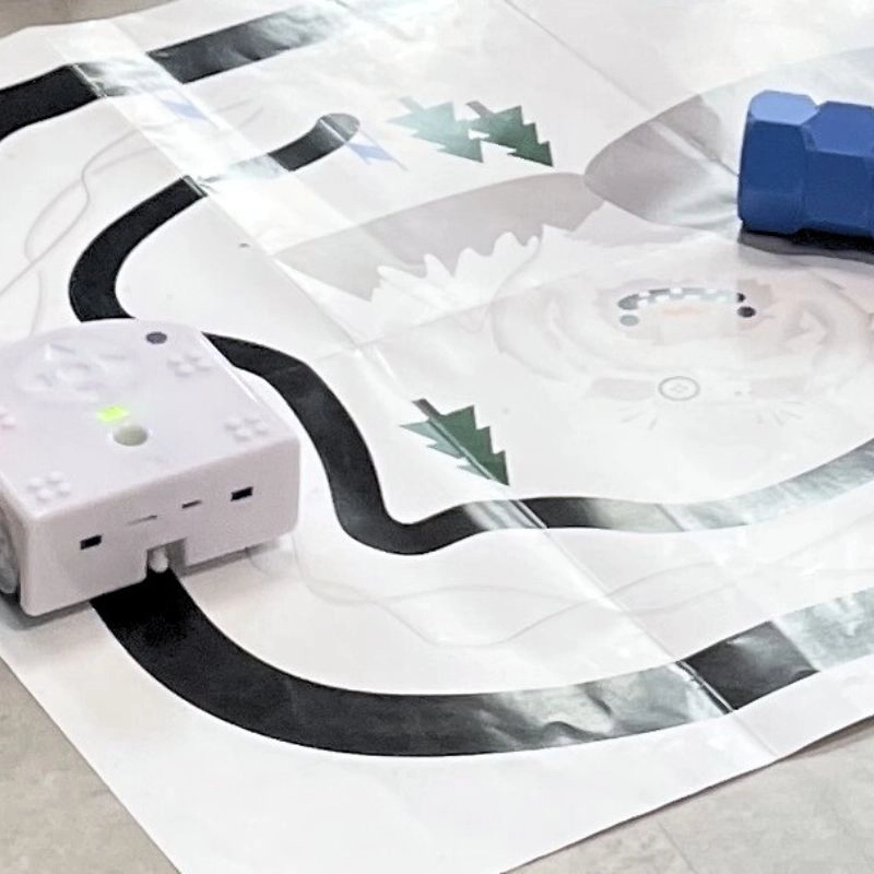 Kleiner Lernroboter folgt einer schwarzen Linie auf einer Spiel- und Lernmatte – Coding-Kurs für Kinder und Einsteiger.