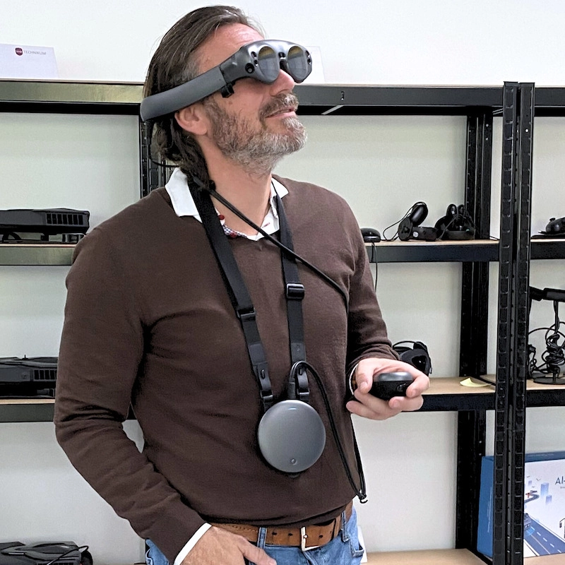 Lehrer testet moderne VR-/AR-Brille mit Controller im Fortbildungszentrum von GAMunich.