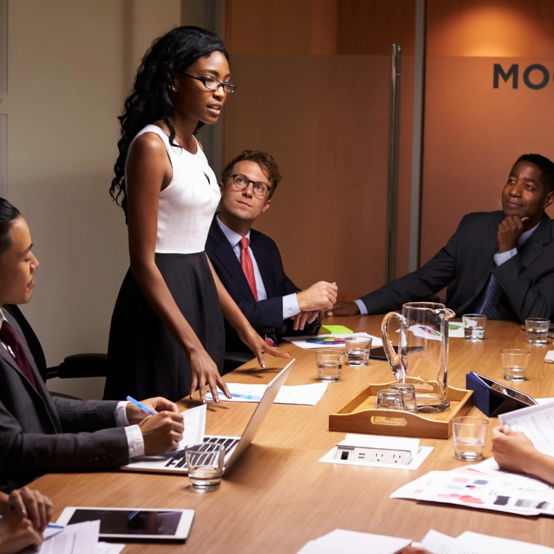 Frau hält eine Präsentation im Konferenzraum vor Geschäftspersonen – Rhetorik- und Kommunikationstraining.